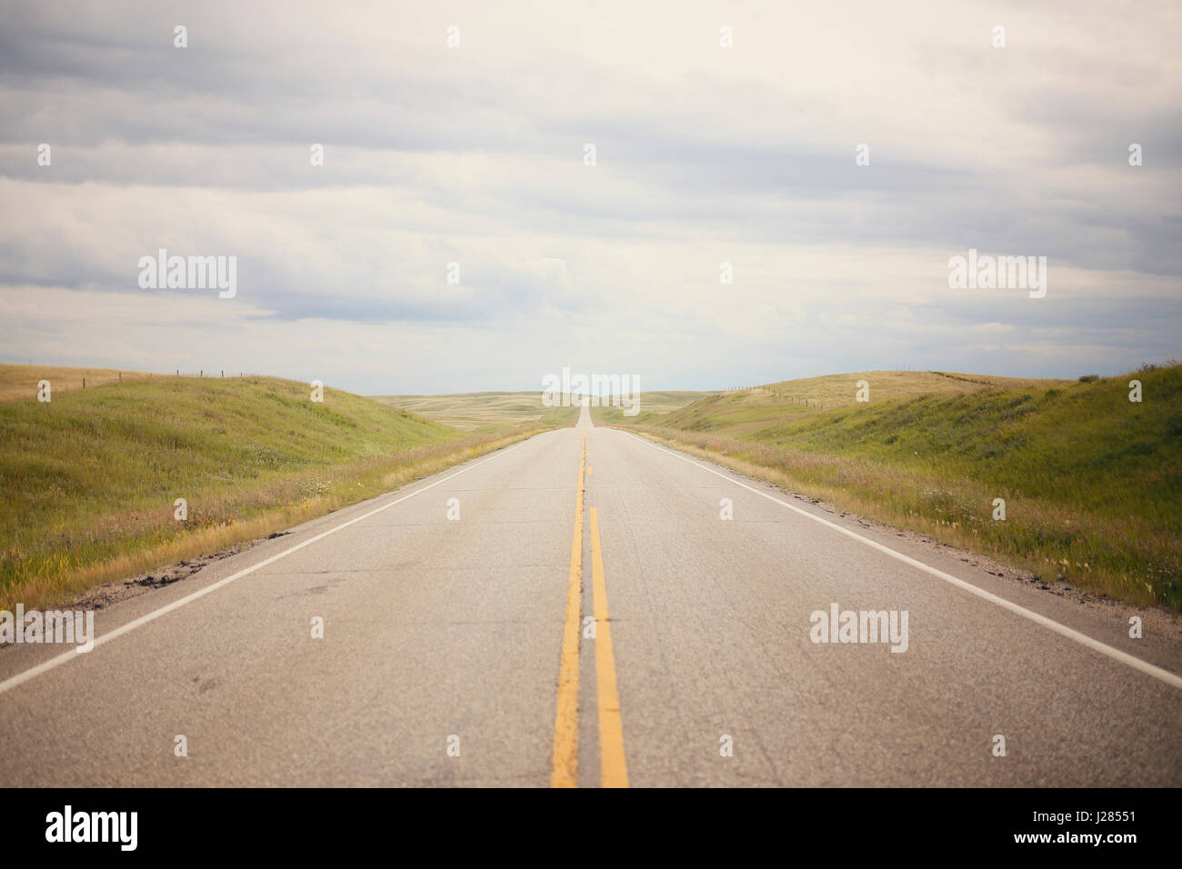 Landstraße inmitten Feld gegen bewölktem Himmel Stockfoto