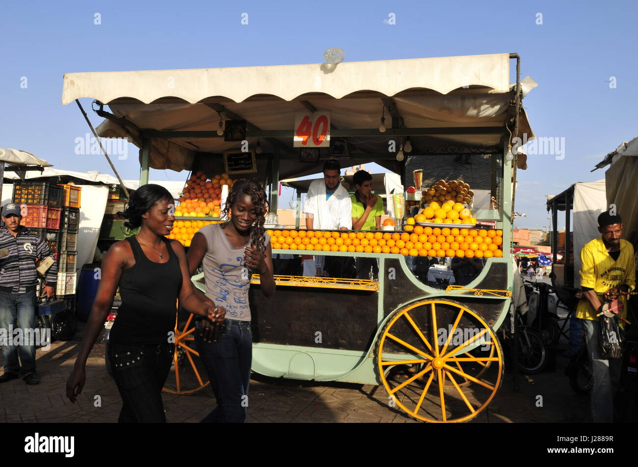 Senegalesischen Frauen gehen durch einen Orangensaft-Lieferanten in der Djema el Fna in Marrakesch. Stockfoto