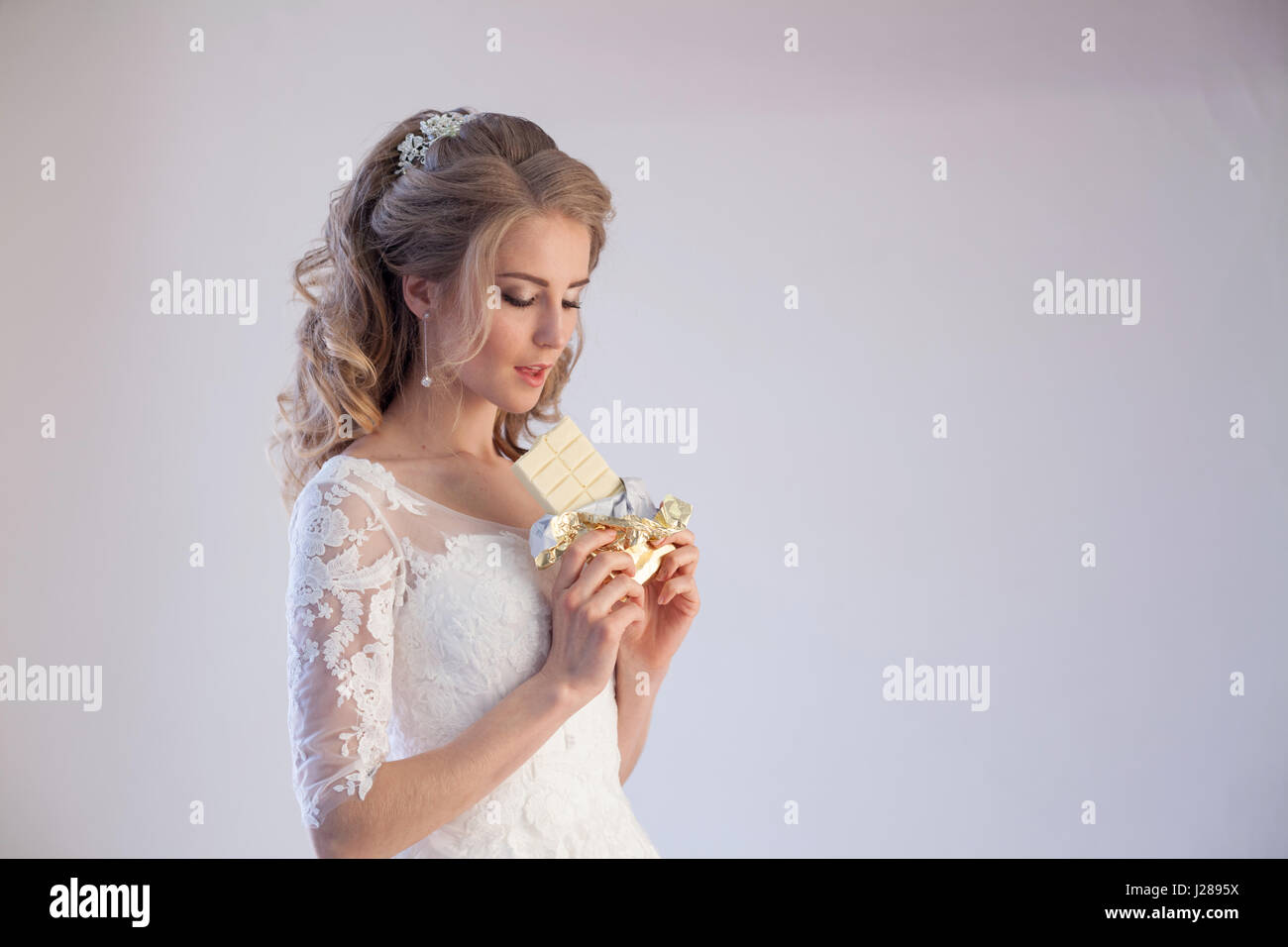 Braut im Hochzeitskleid halten eine Schokolade Stockfoto