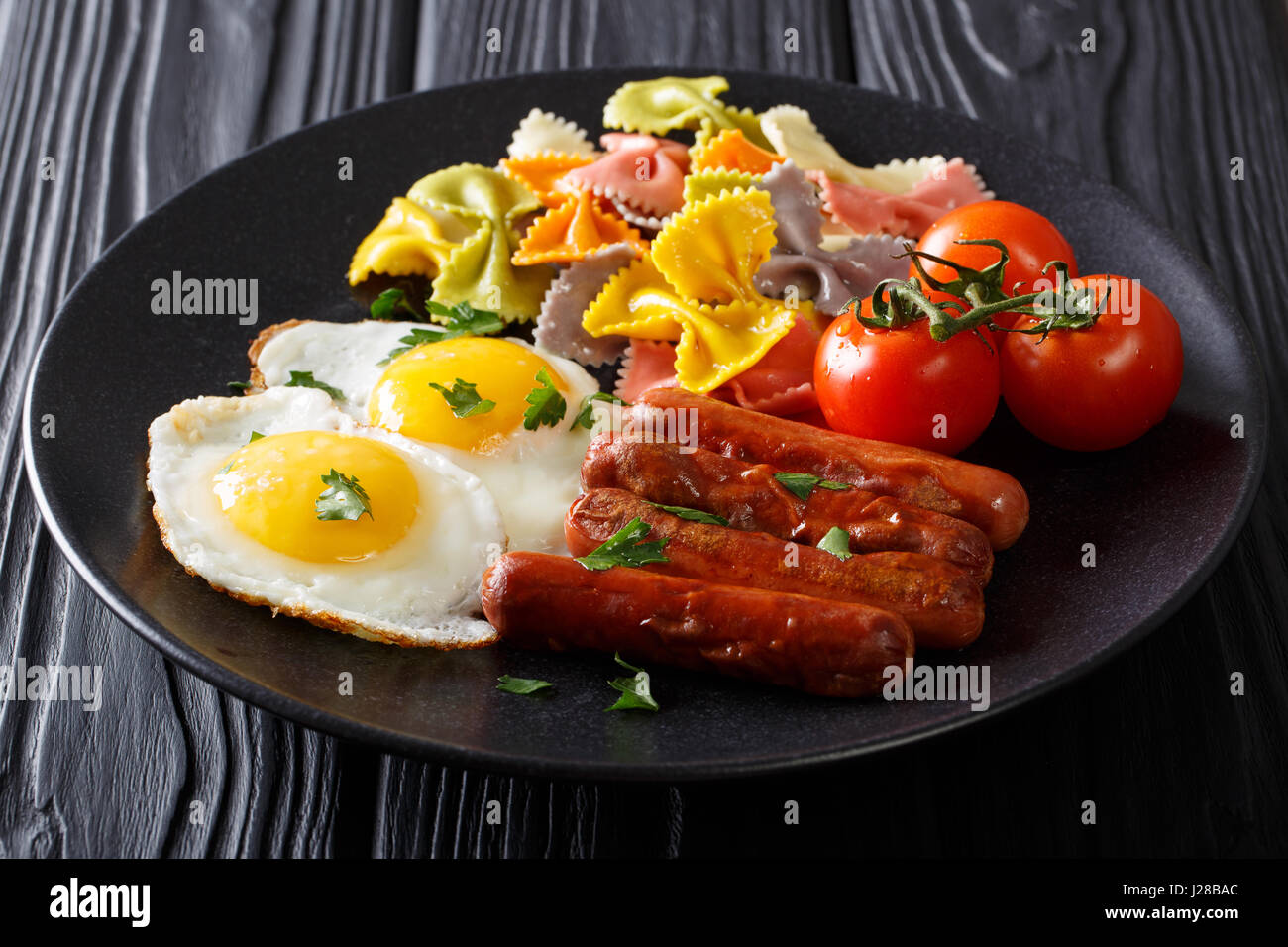 Farfalle-Nudeln mit gebratenen Eiern und Würstchen Nahaufnahme auf einer Platte. horizontale Stockfoto