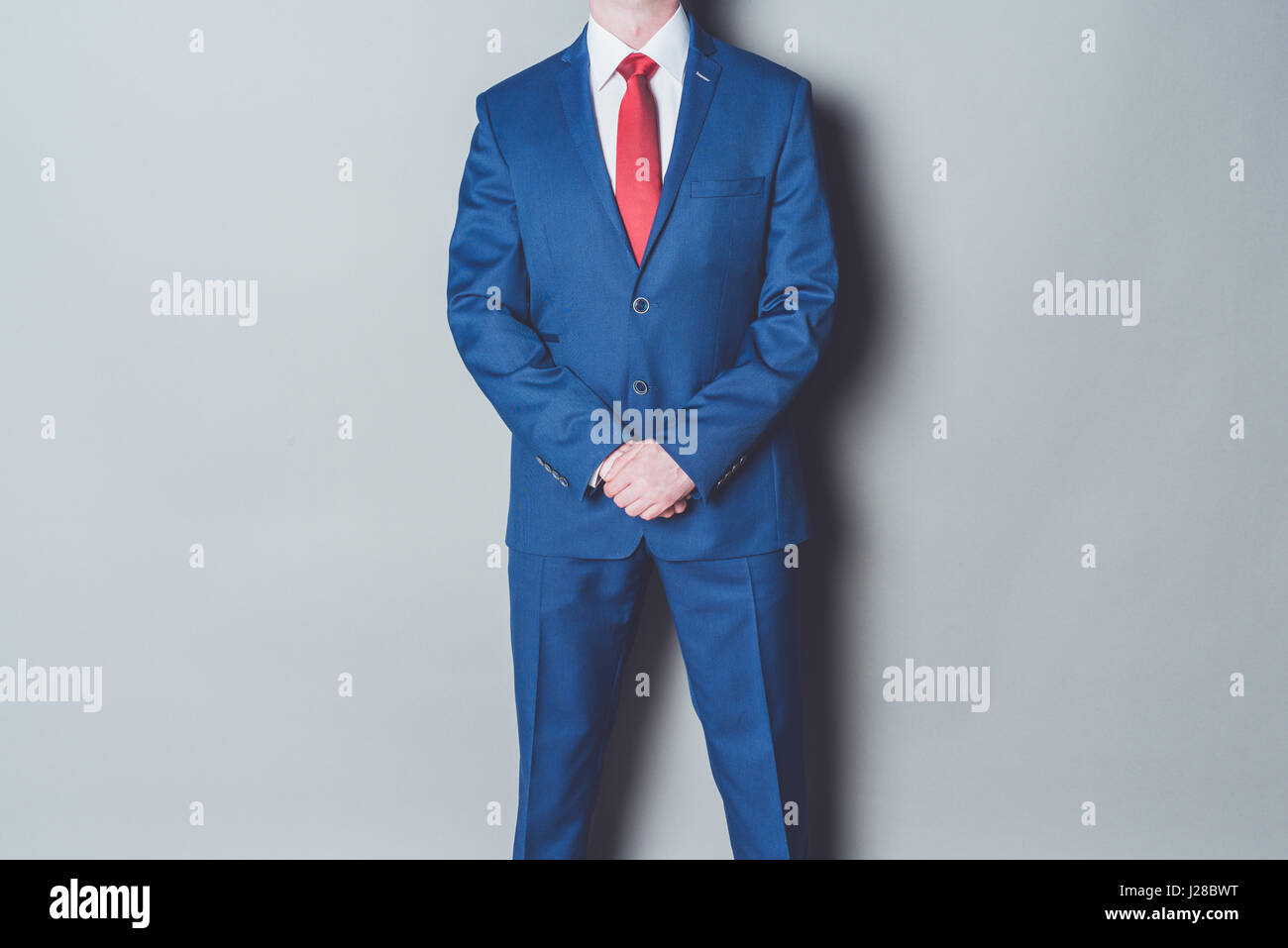 Porträt der erfolgreiche Geschäftsmann trägt blaue siut und roten Riegel gegen grauer Hintergrund Stockfoto