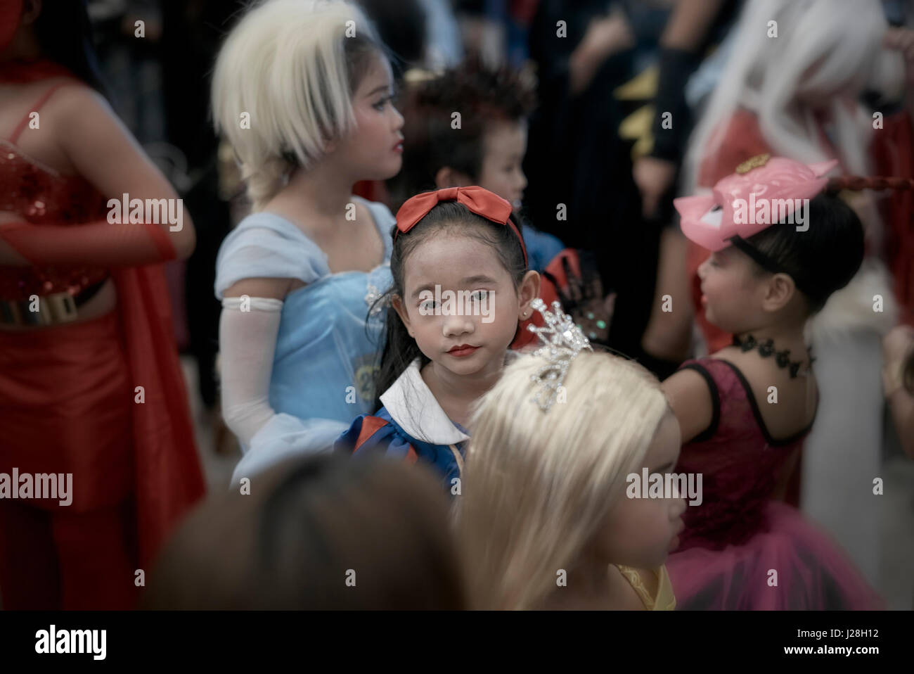 Kind allein in einer Menschenmenge von Cosplay Teilnehmer und mit einem Gesichtsausdruck zeigen, dass sie offenbar gelangweilt ist.  Bangkok, Thailand, 2017 Stockfoto