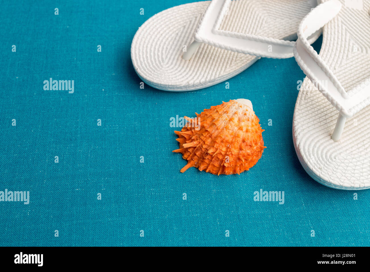 Weiß flip flop in der Nähe von Muschel auf blauem Hintergrund. Textfreiraum Stockfoto