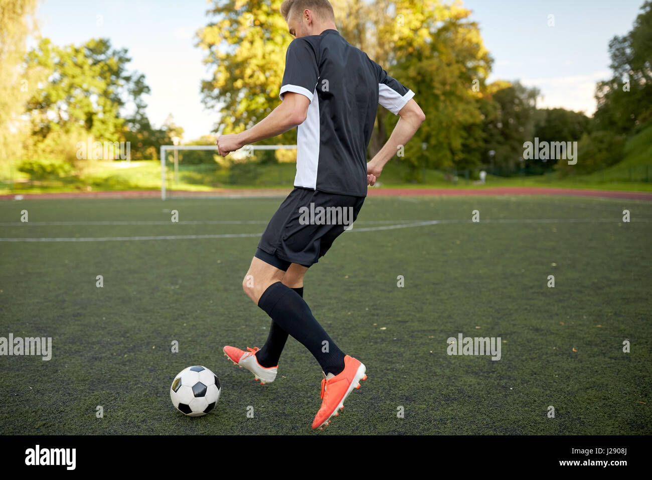 Fußballspieler mit Ball auf Fußballplatz spielen Stockfoto