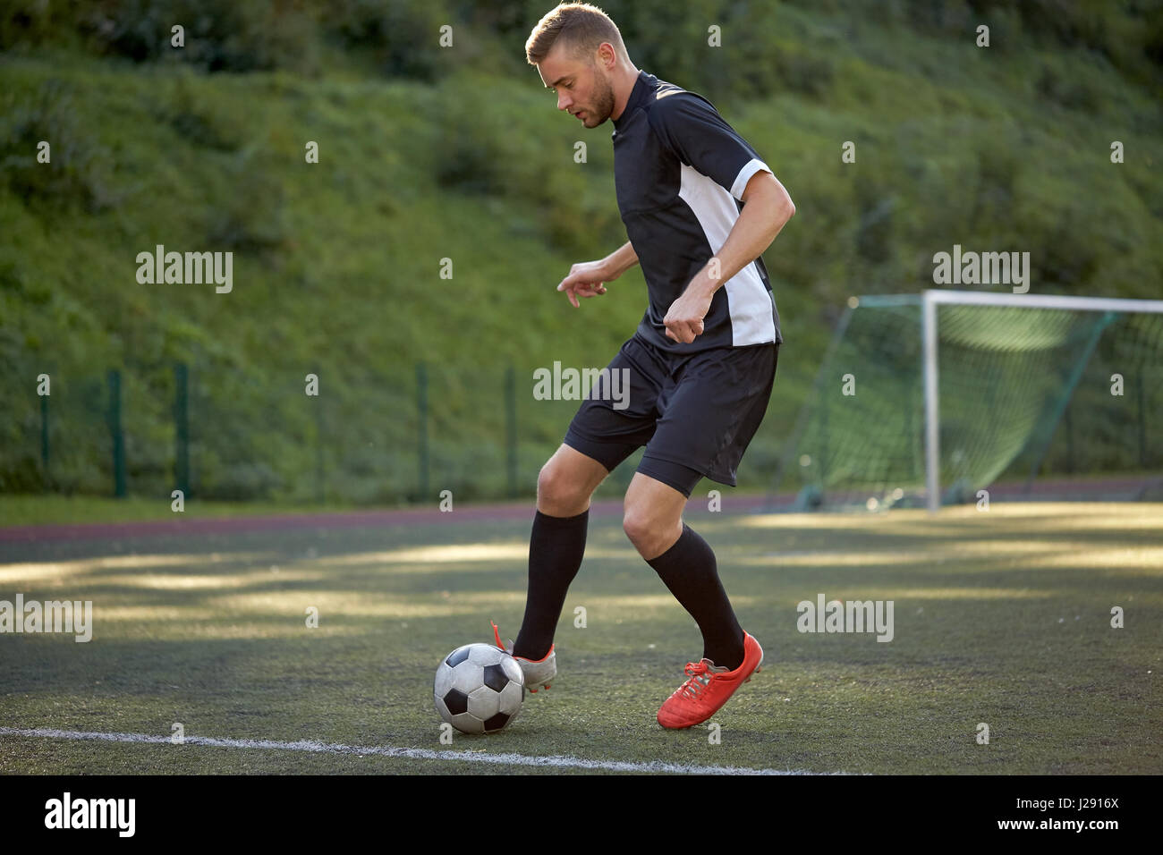 Fußballspieler mit Ball auf Fußballplatz spielen Stockfoto