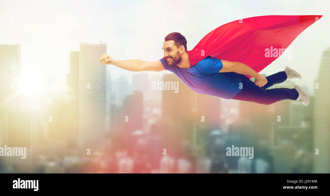 glücklicher Mann im roten Superhelden Kap fliegen in der Luft Stockfoto
