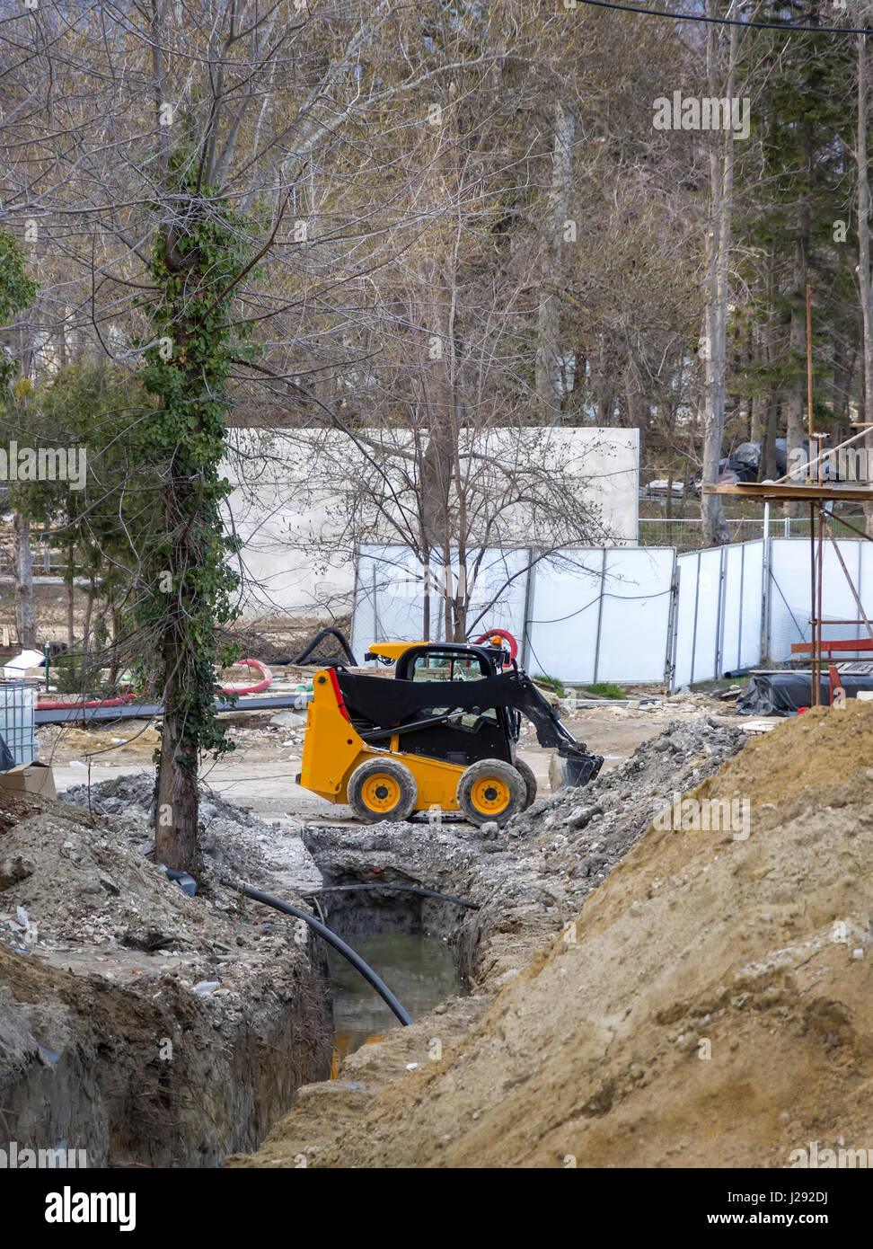 Tagesansicht des gelben Minibagger mit Schaufel in Aktion auf der Baustelle Stockfoto