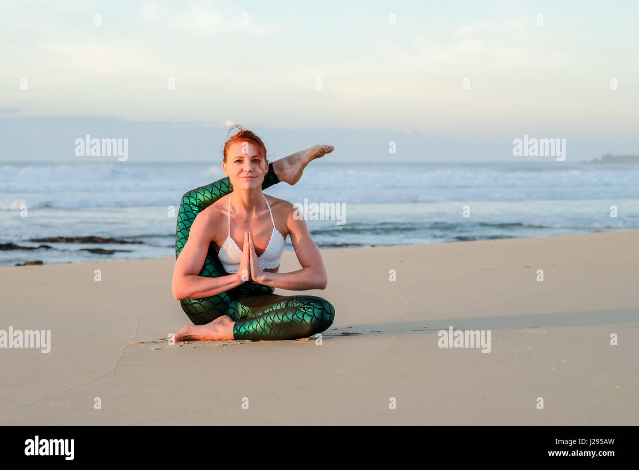 Ein Yogi oder Yoga Meister Lehrer übt bei Sonnenaufgang am Strand und zeigt ihre Stärke, Kontrolle und Technik in den frühen Morgenstunden. Stockfoto