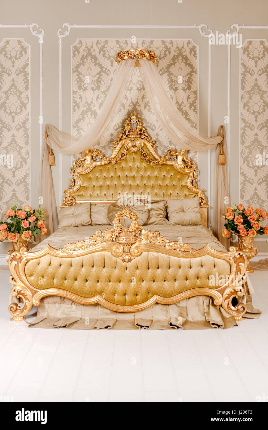 Luxus Schlafzimmer in hellen Farben mit goldenen Möbel Details. Große komfortable Doppelzimmer Königsbett in eleganten klassischen Interieur Stockfoto
