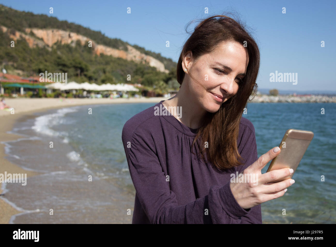 Frau, die ihre mobile am Strand suchen, lächelnd. Stockfoto