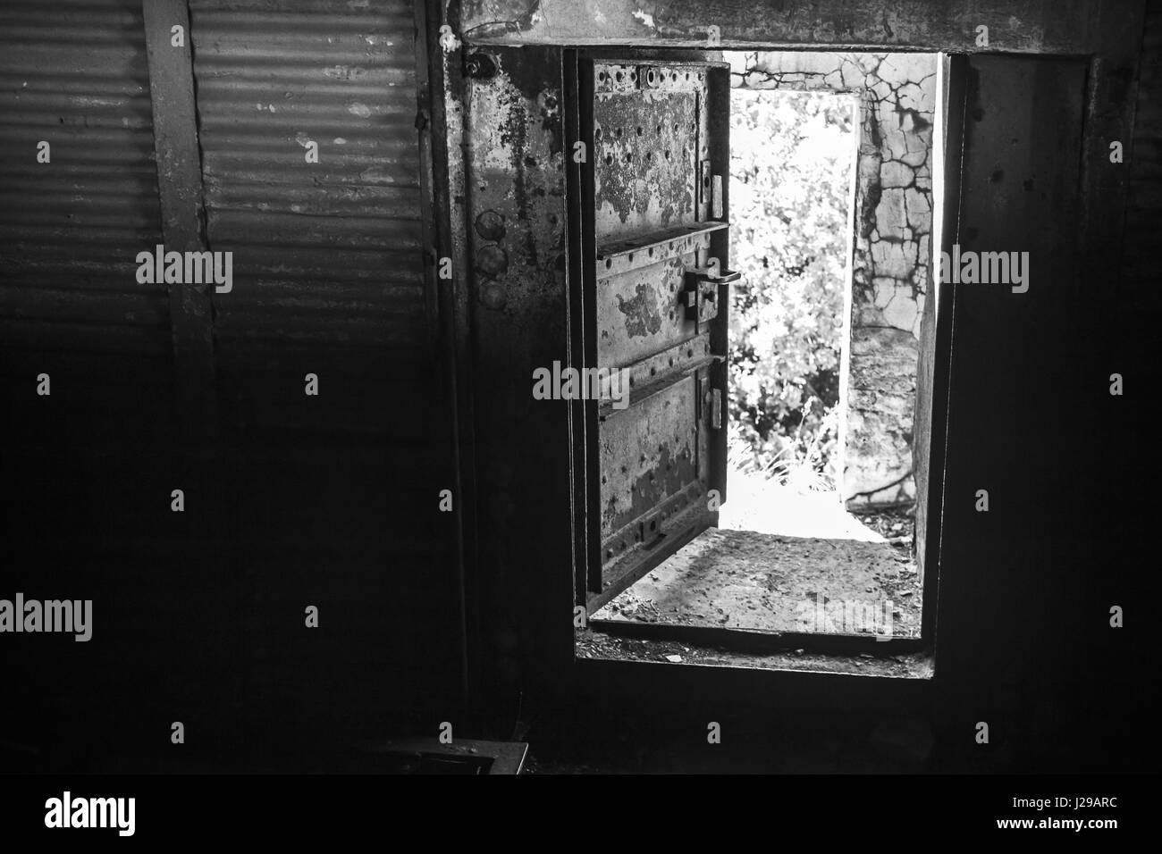Abstrakte Dunkle grungy industrielle Interieur mit Metallwänden und schwere Stahltür, schwarz / weiß Foto öffnen Stockfoto