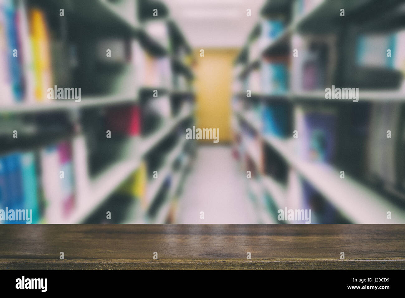 Innenraum der modernen Bibliothek mit grauen Buchregale, Unschärfe Hintergrund mit selektiven Fokus Holztisch für die Anzeige Ihres Produkts Stockfoto