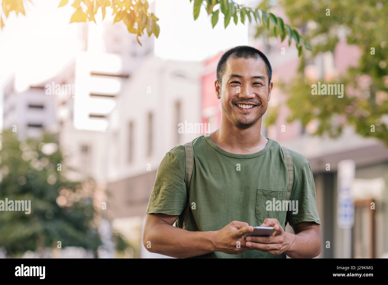 Junge asiatische Mann eine SMS auf sein Handy außerhalb Stockfoto