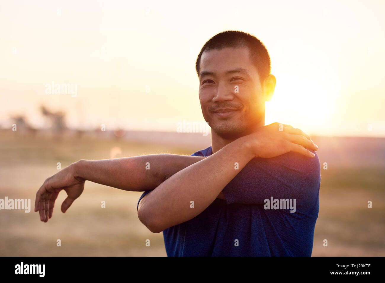 Jungen asiatische Mann streckte die Arme vor einem Lauf zu passen Stockfoto