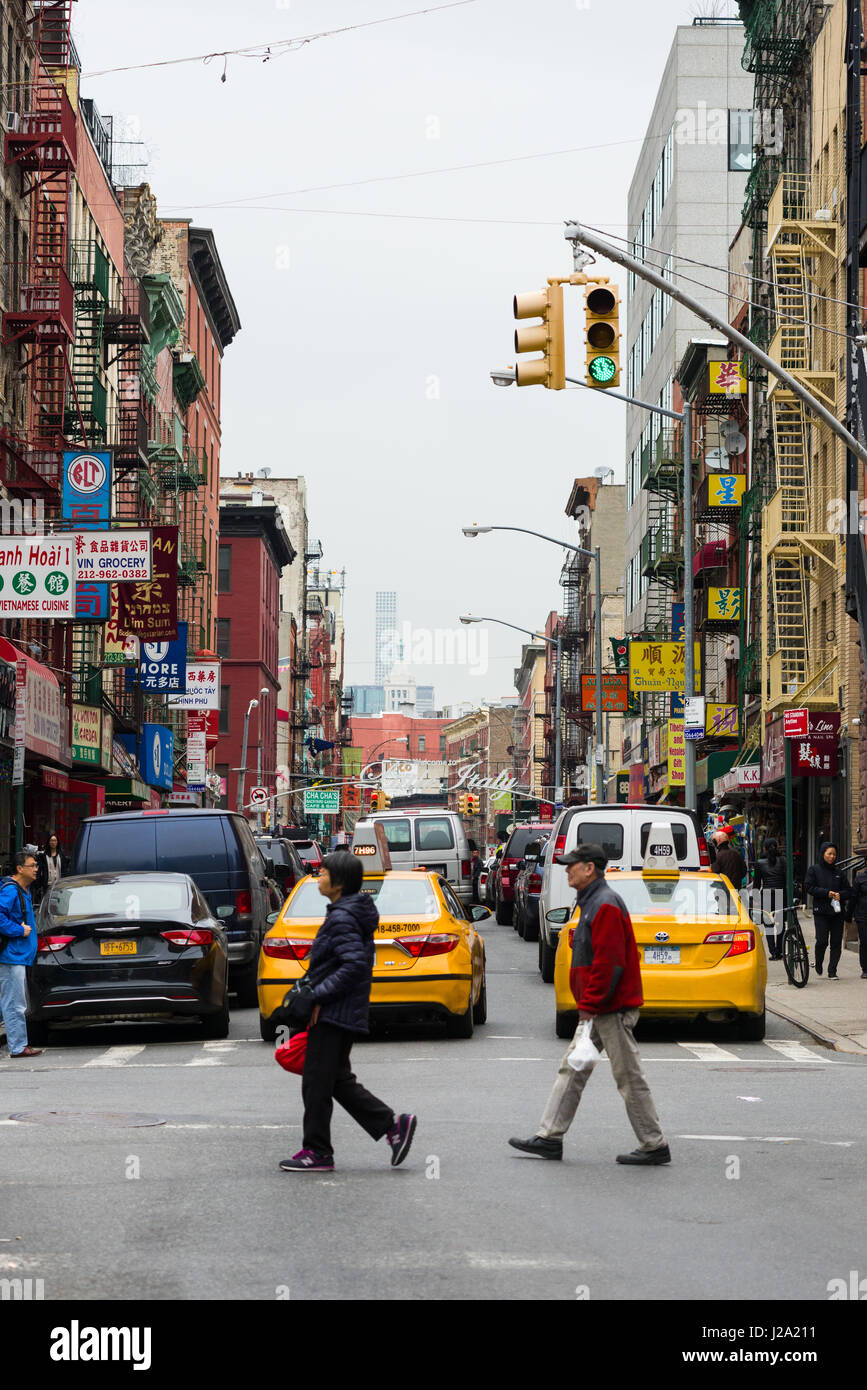 Menschen Überqueren einer Straße mit Gebäuden und Fahrzeugen im Hintergrund, Chinatown, Manhattan, New York Stockfoto