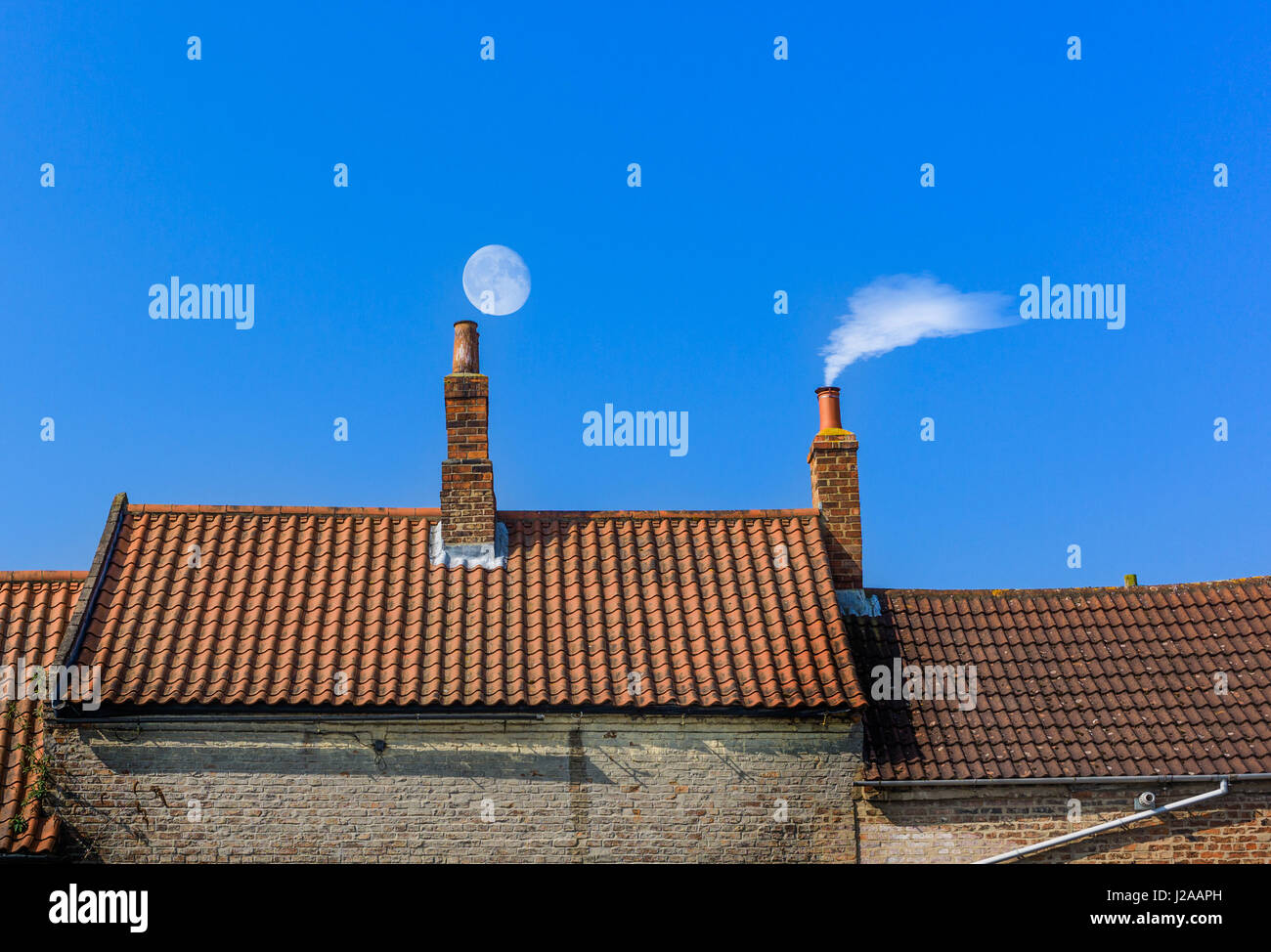 Schornstein-Dachlinie mit Mond und Rauch Stockfoto