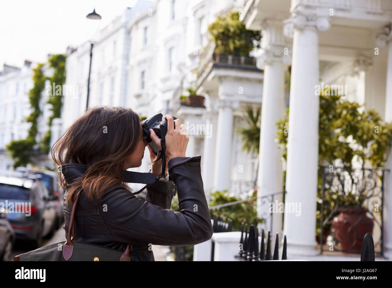Junge Frau nehmen Foto in einer Residenzstadt Straße, Seitenansicht Stockfoto