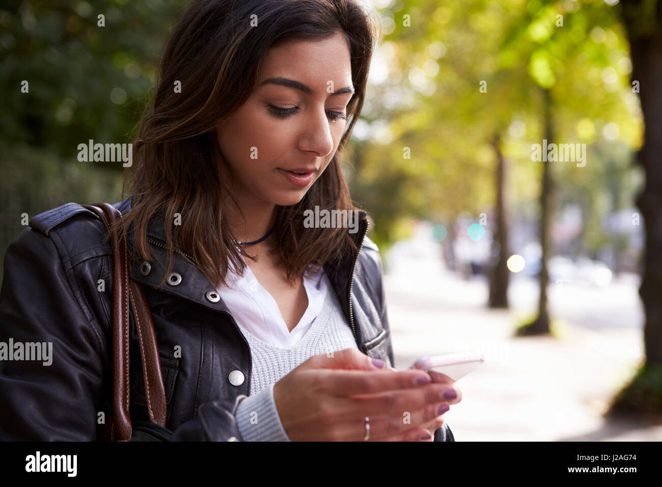 Junge Frau, die in der Straße mit Handy, Nahaufnahme Stockfoto