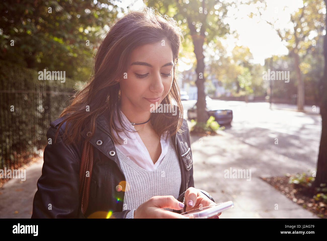 Junge Frau, die in der Straße mit Handy, wieder beleuchtet in der Nähe Stockfoto