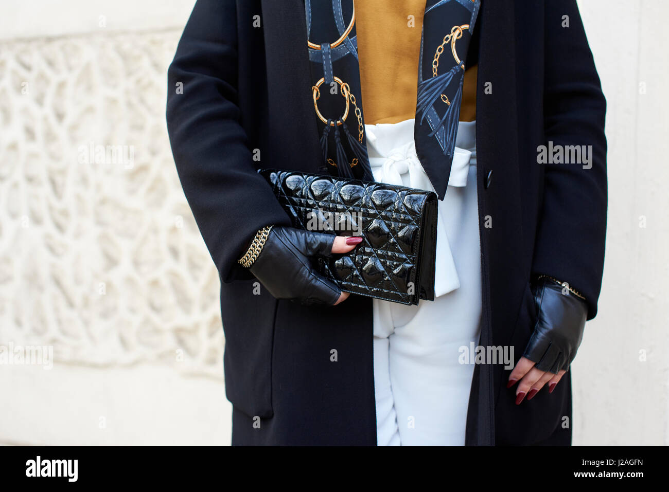 LONDON - Februar 2017: Mittelteil der Frau im Mantel und fingerlose Handschuhe halten eine Chanel Clutch Handtasche auf der Straße während der London Fashion Week, horizontal, Frontansicht Stockfoto
