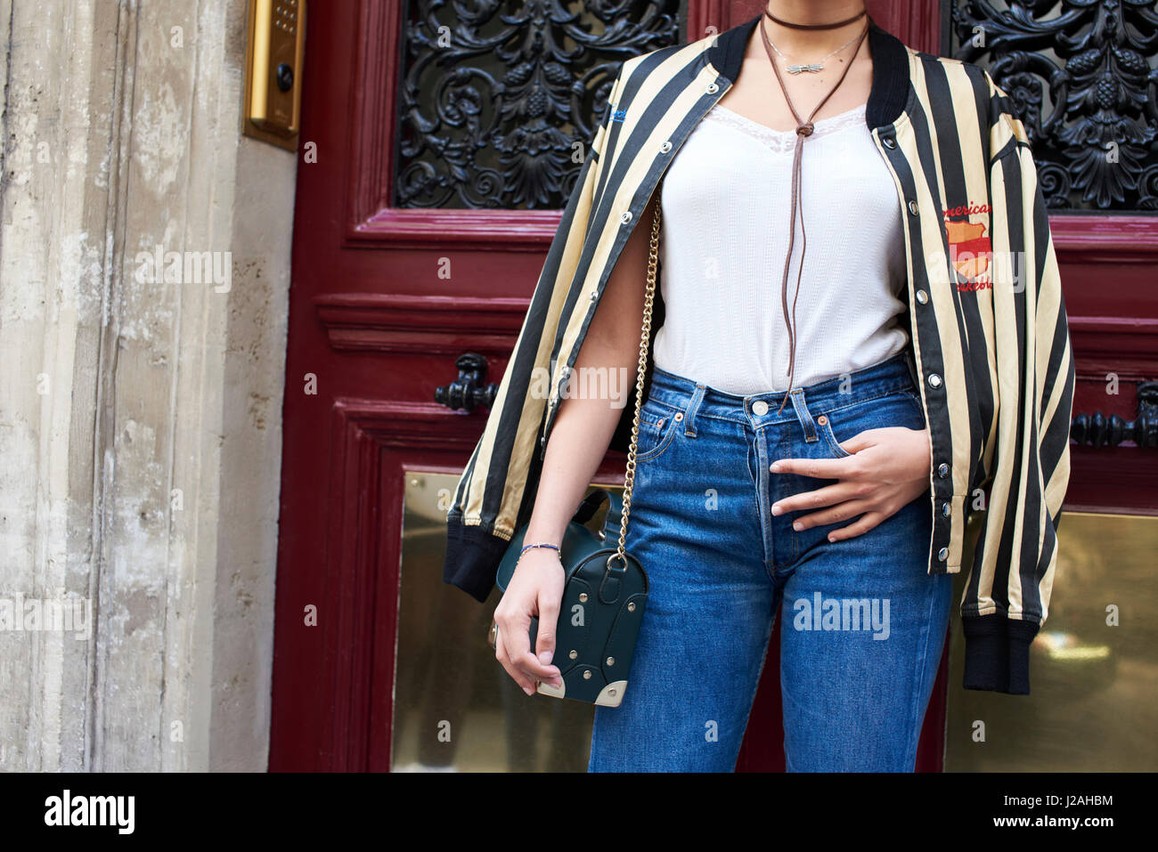 Frau mit Baseballjacke über Schultern steht in Tür Stockfoto