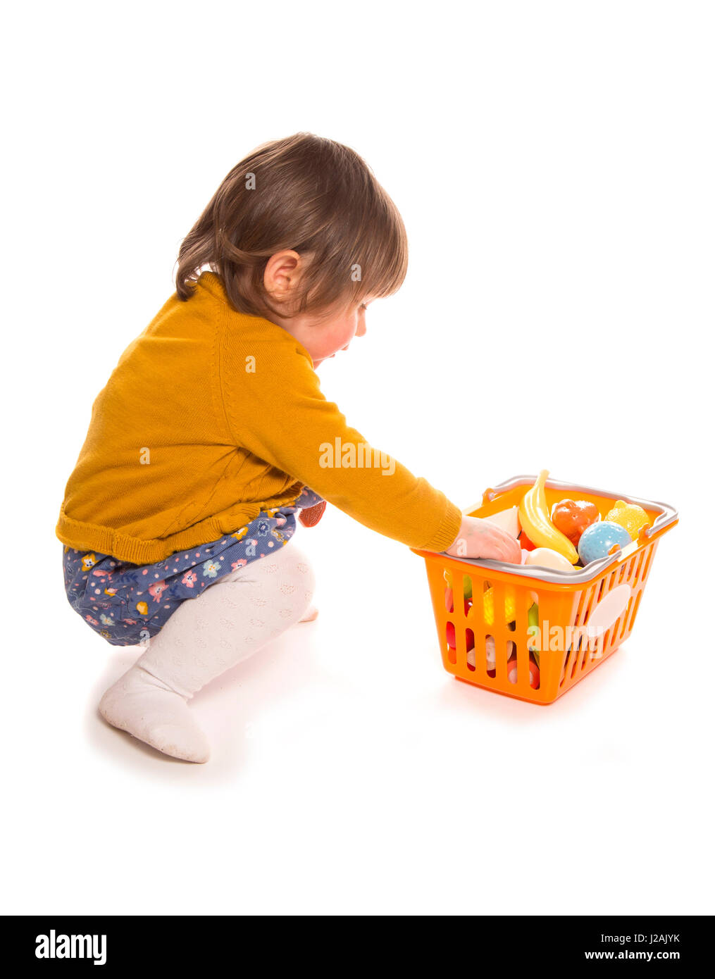 Kleinkind spielt mit Kunststoff-Lebensmittel-Ausschnitt Stockfoto