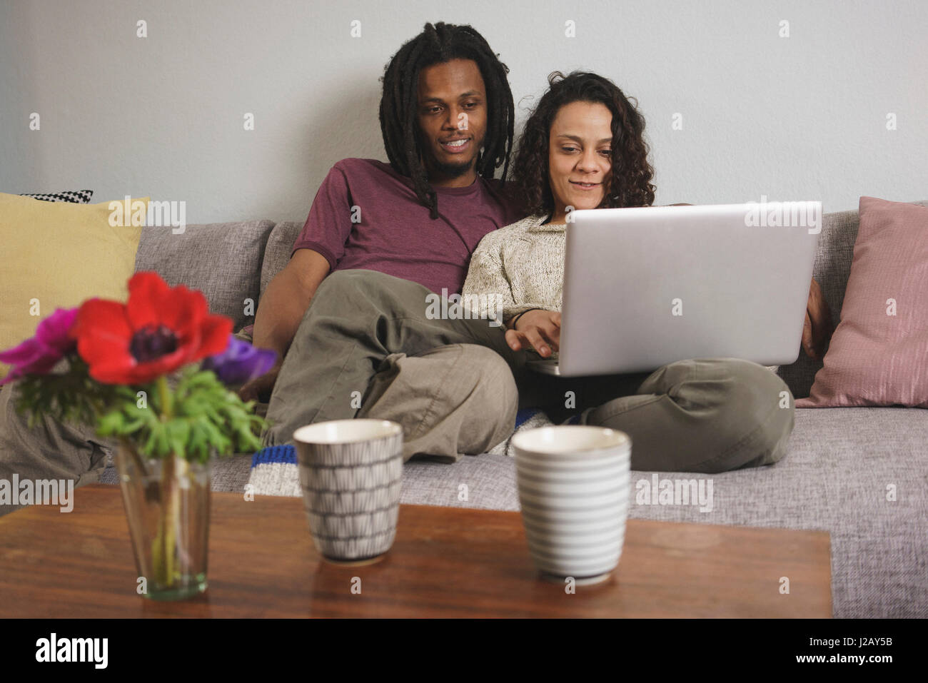 Multi-ethnischen Pärchen mit Laptop sitzend auf Sofa zu Hause Stockfoto