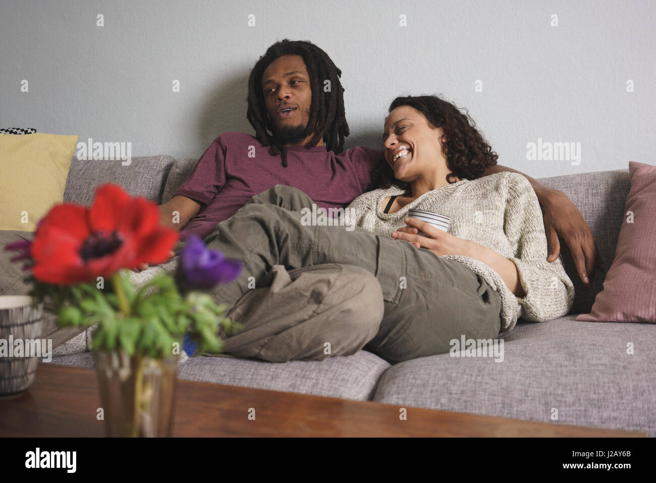 Fröhliche multiethnischen paar entspannende zu Hause auf sofa Stockfoto