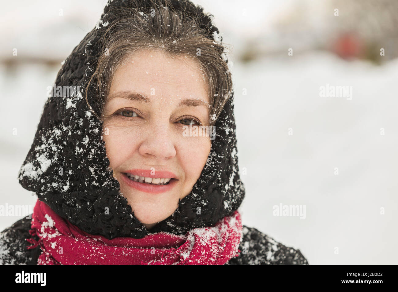 Porträt der lächelnde ältere Frau in Winterkleidung mit Schnee bedeckt Stockfoto