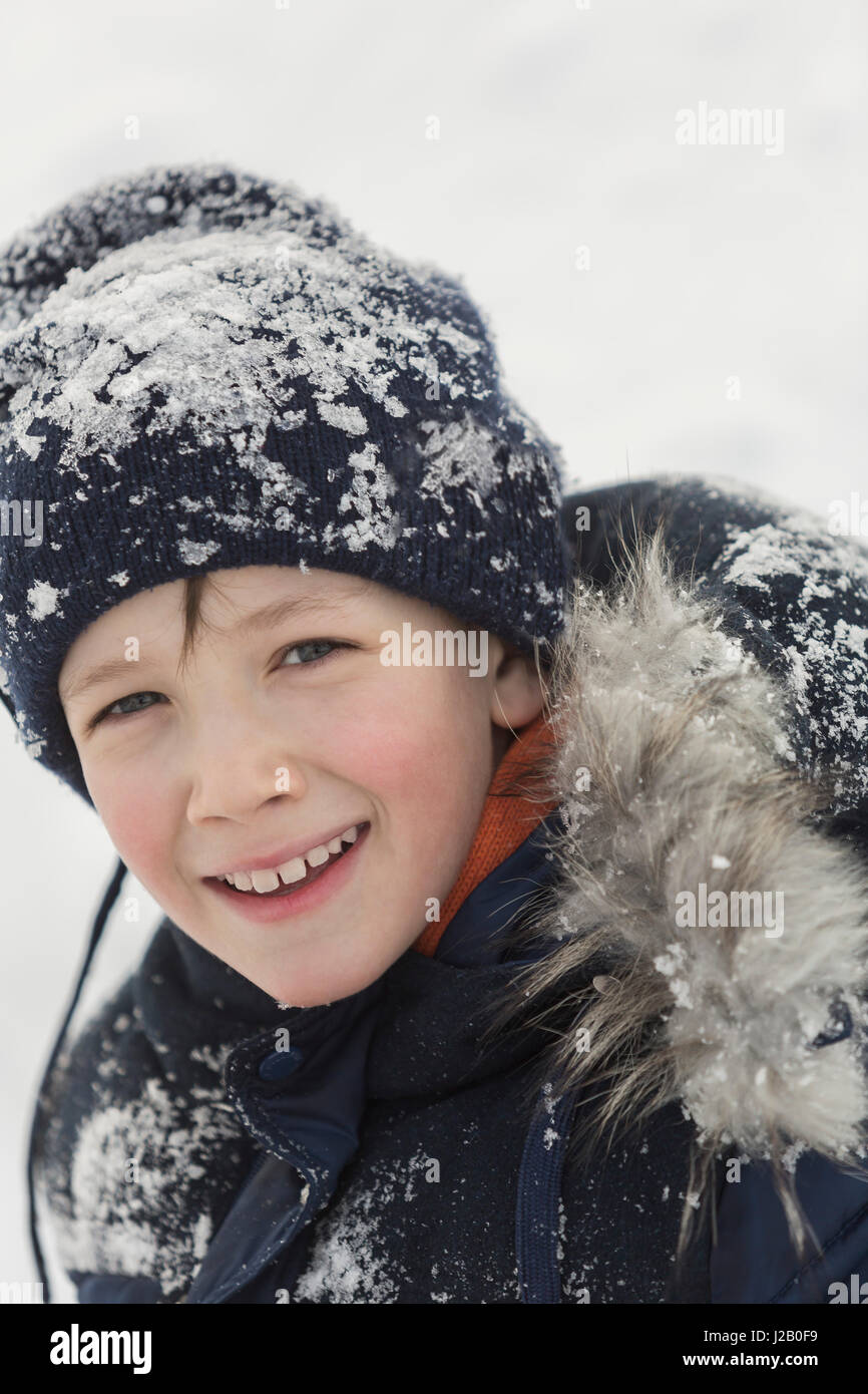 Porträt von fröhlicher Junge im Winter tragen mit Schnee bedeckt Stockfoto