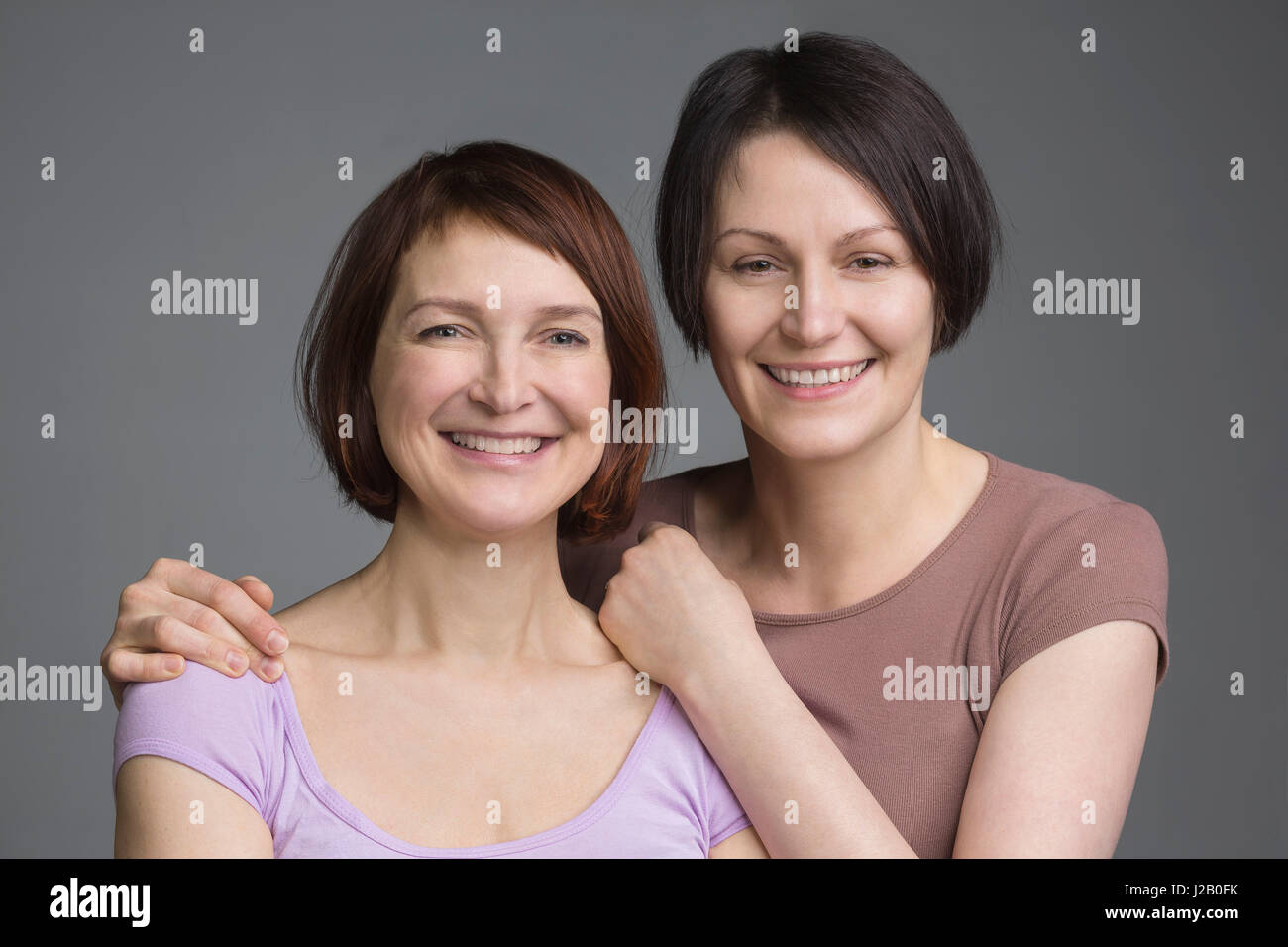 Porträt von glücklich Reifen Freundinnen vor grauem Hintergrund Stockfoto