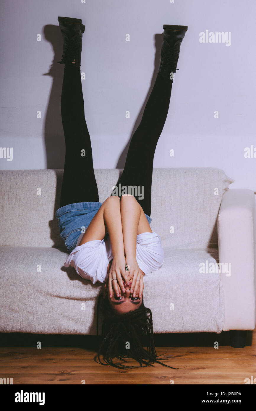 Frau liegend auf Sofa mit Füßen gegen weiße Wand Stockfoto