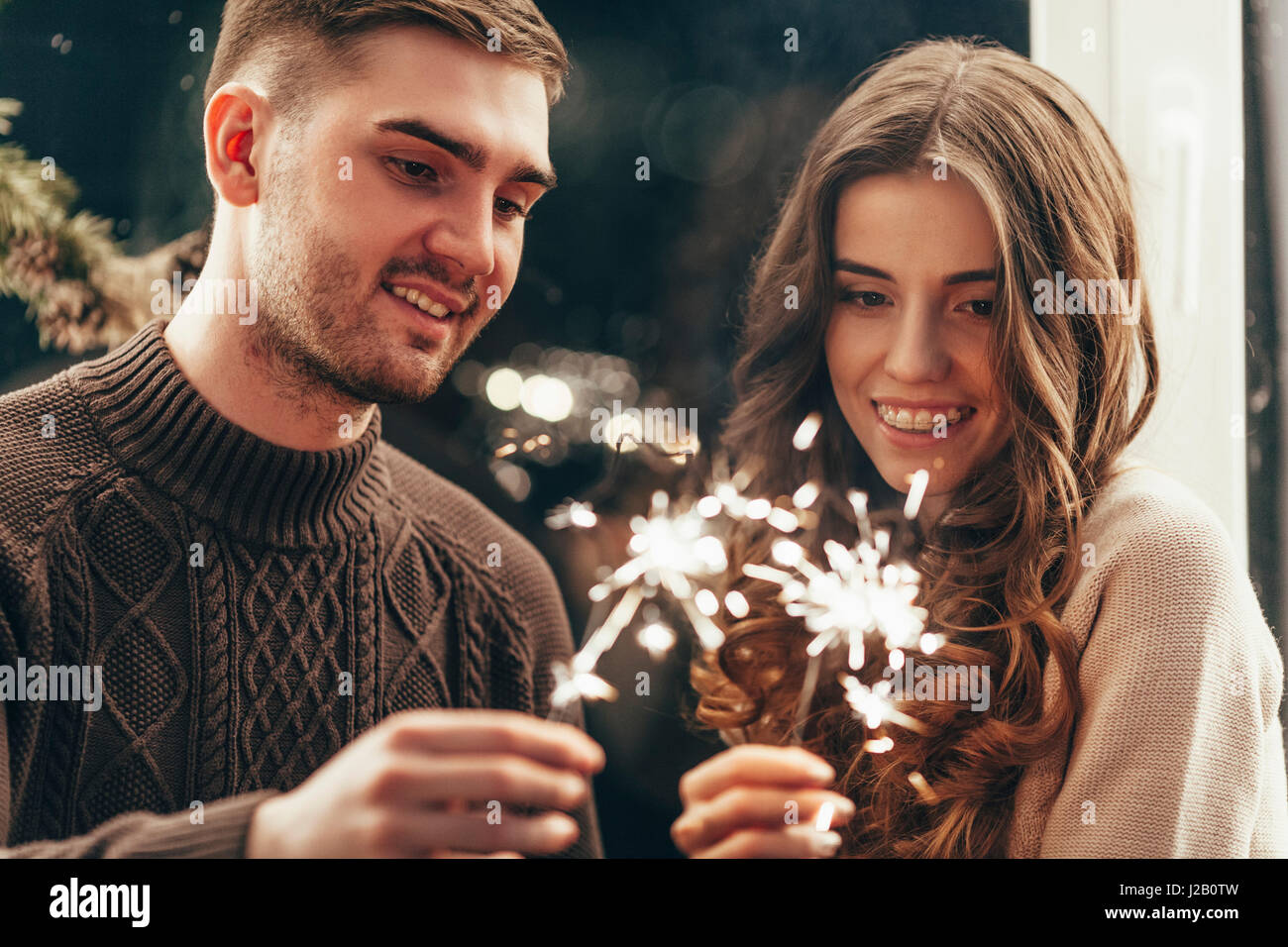 Lächelnde paar spielen mit Wunderkerzen während der Weihnachtsfeier Stockfoto