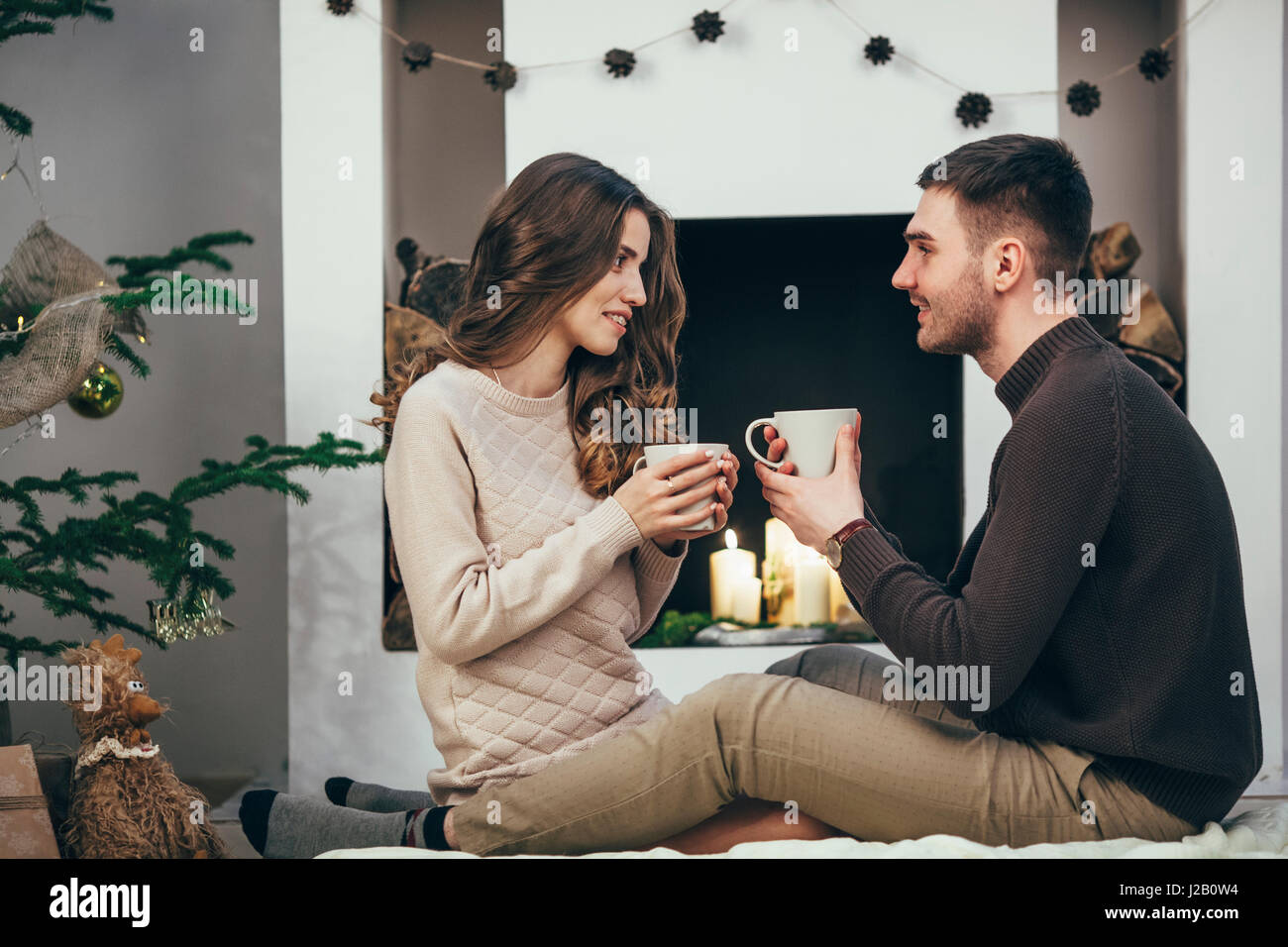 Lächeln, paar mit Kaffee sitzend auf Teppich zu Hause während der Weihnachtszeit Stockfoto