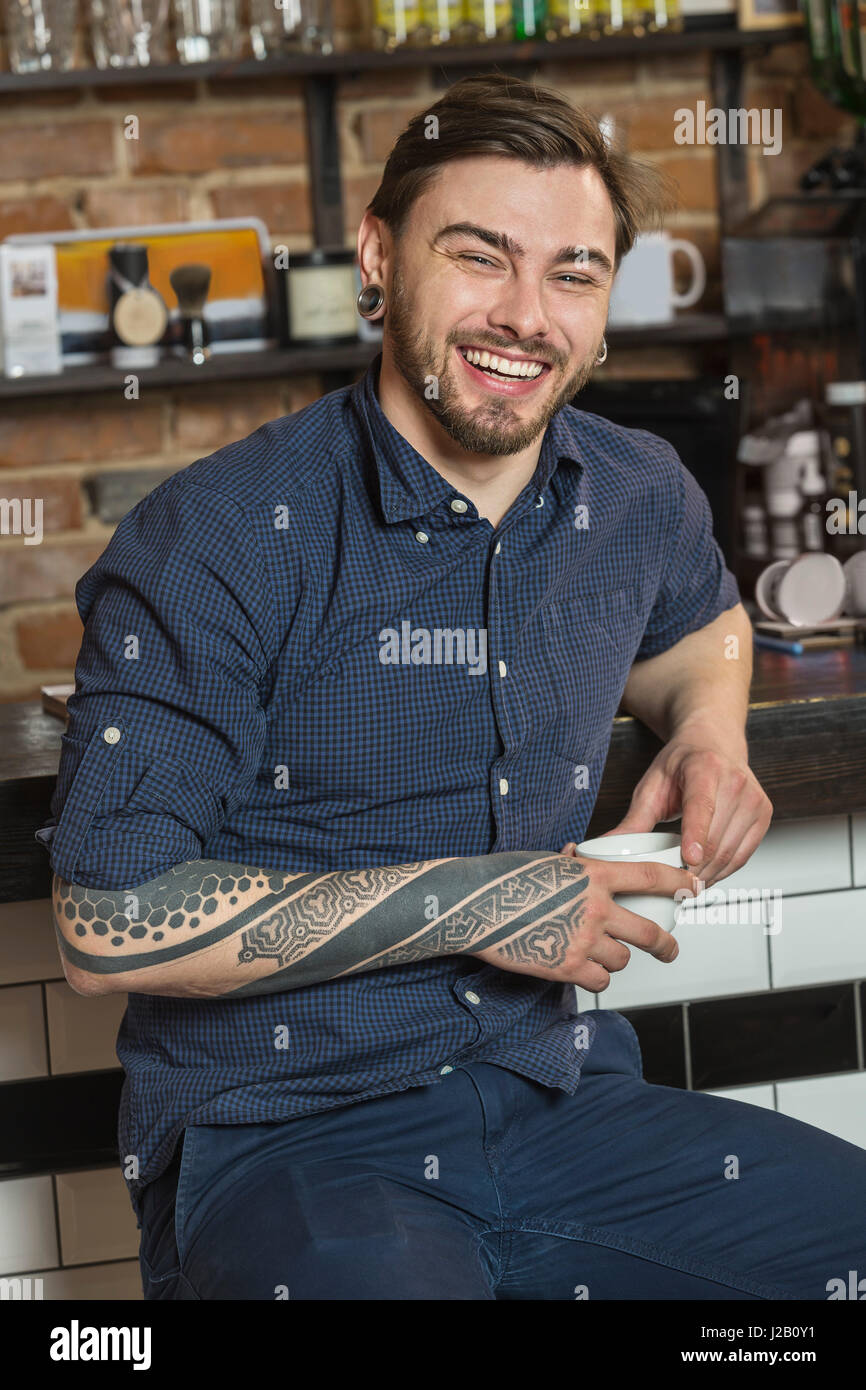Porträt von fröhlichen Friseur sitzen mit Kaffee am Tresen im Friseurladen Stockfoto