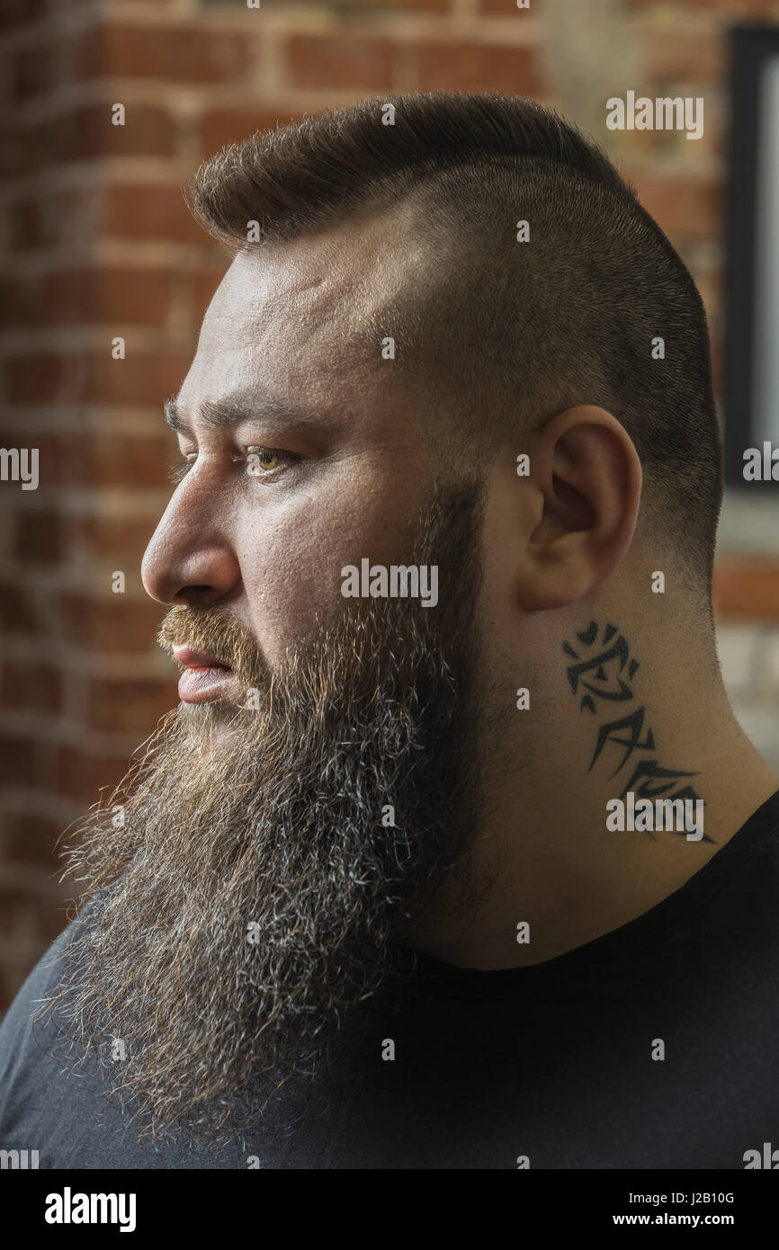 Nahaufnahme des männlichen Friseur mit Tattoo und Bart wegsehen bei Friseur Stockfoto