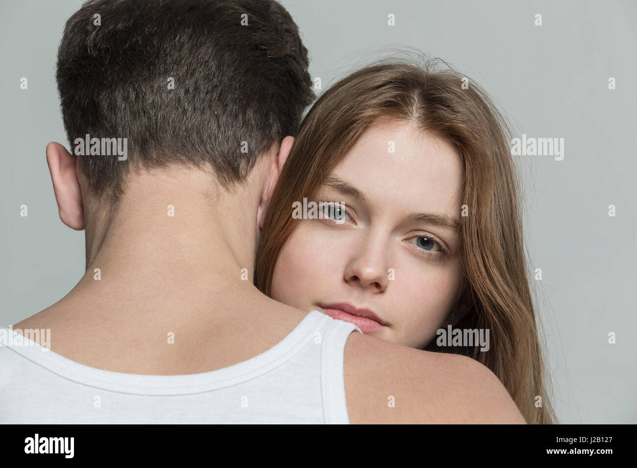 Porträt der Frau umarmen Freund vor grauem Hintergrund Stockfoto