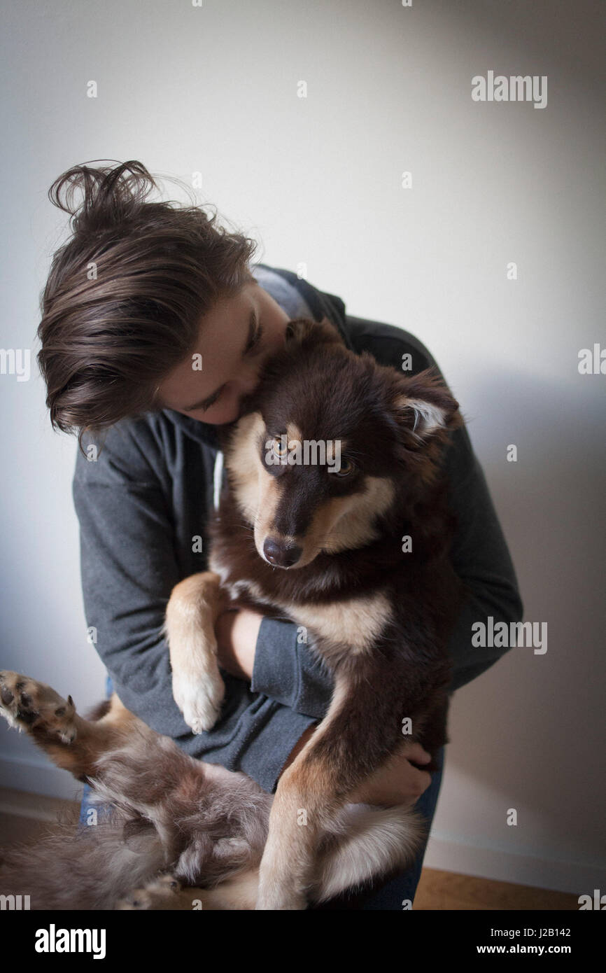 Zärtliche junge Frau umarmen Hund vor weißem Hintergrund Stockfoto