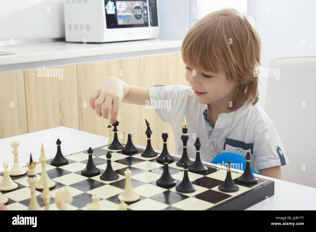 Wenig kluger Junge konzentriert und denken mit Schach Stockfoto