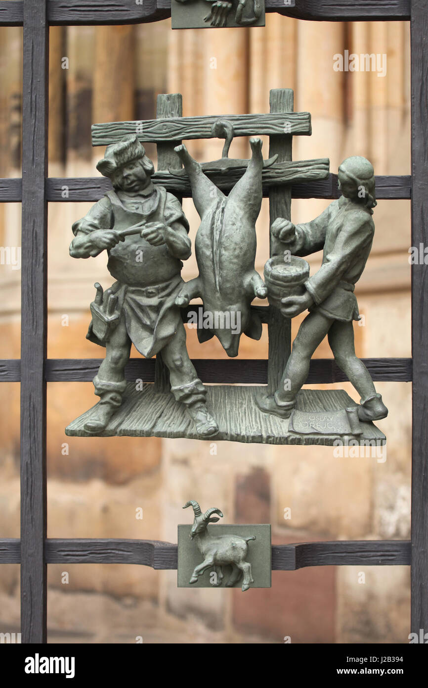 Schwein Schlachten im Winter. Allegorie der Jahreszeiten von tschechischer Bildhauer Jaroslav Horejc (1954-1957) für die dekorative Bronze Grille von der Golden Gate Saint Vitus Kathedrale in Prag, Tschechische Republik entworfen. Stockfoto