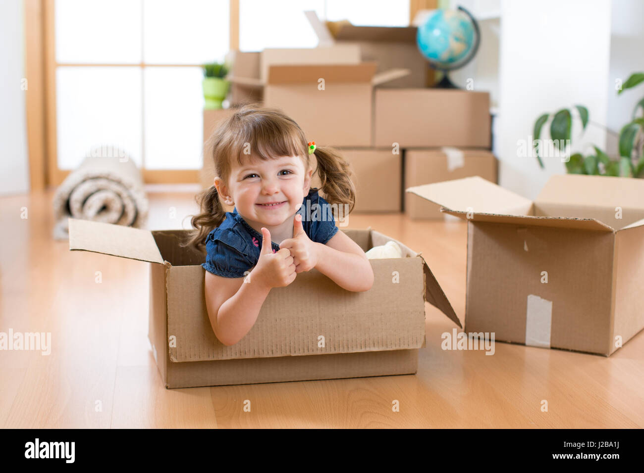Umzug in neue Wohnung. Glückliches Kind im Karton. Stockfoto