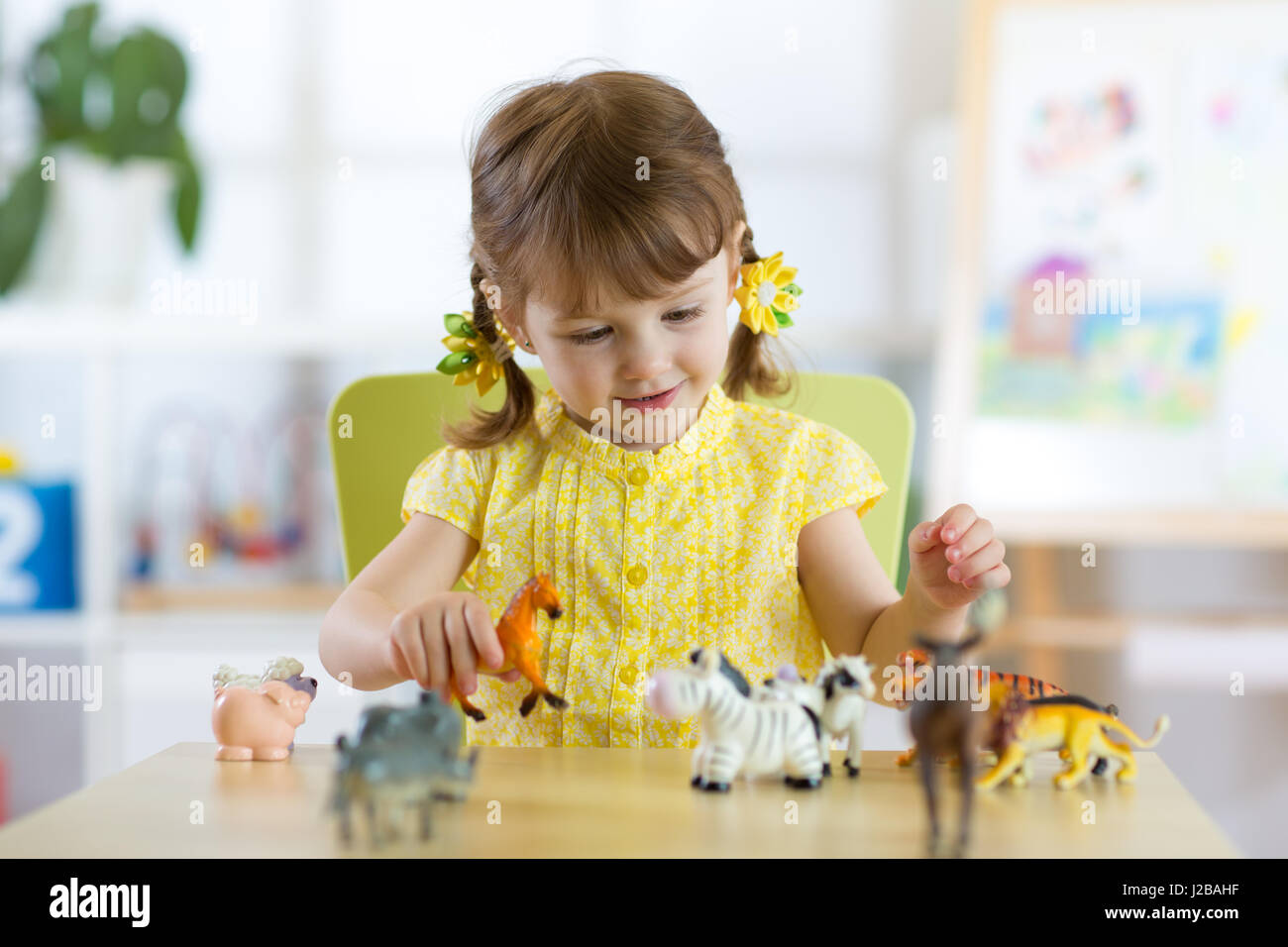 Glückliches kleines Mädchen. Lächelndes Kind Kleinkind spielt tierisches Spielzeug zu Hause oder im Kindergarten. Stockfoto