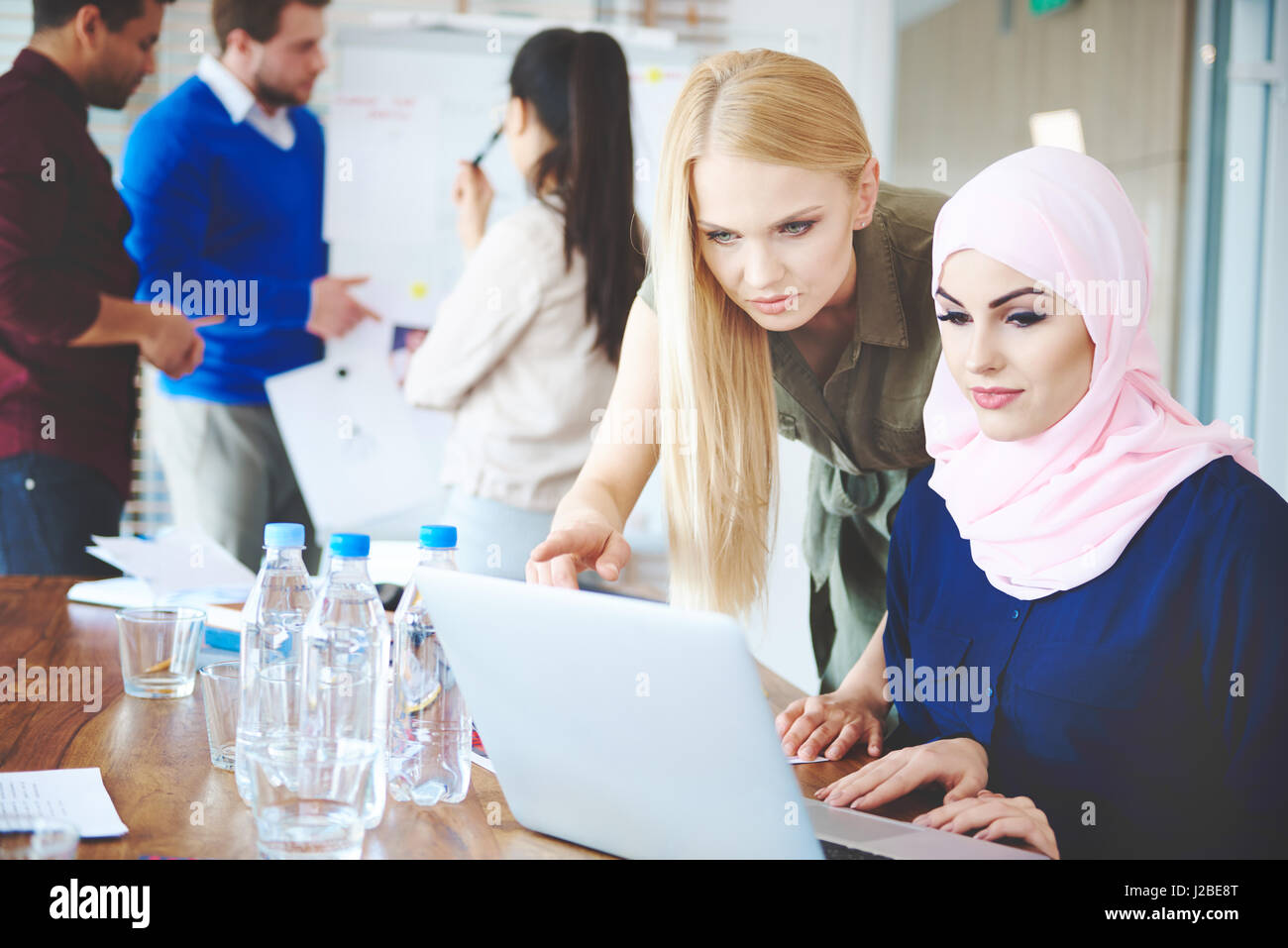 Die muslimische Frau, die Arbeit am Laptop mit Kollegen Stockfoto