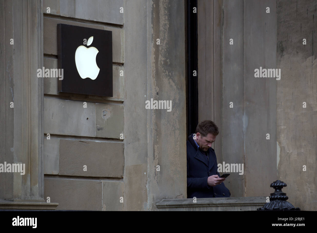 Apple-Shop-Logo auf Sandsteingebäude Glasgow Mann auf dem iphone Stockfoto