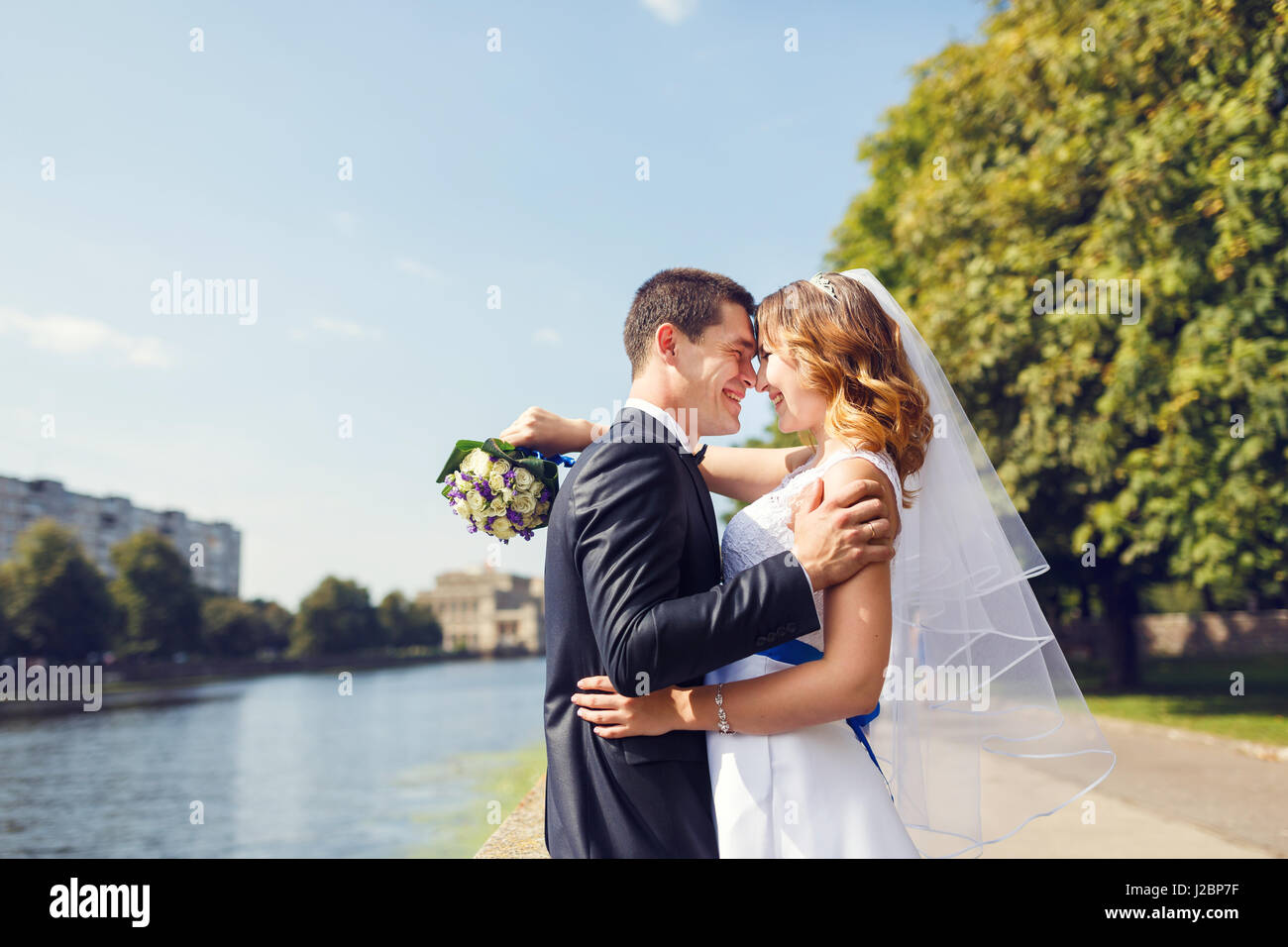 Junge Brautpaar ist in einem Park im Sommer umarmt. Stockfoto
