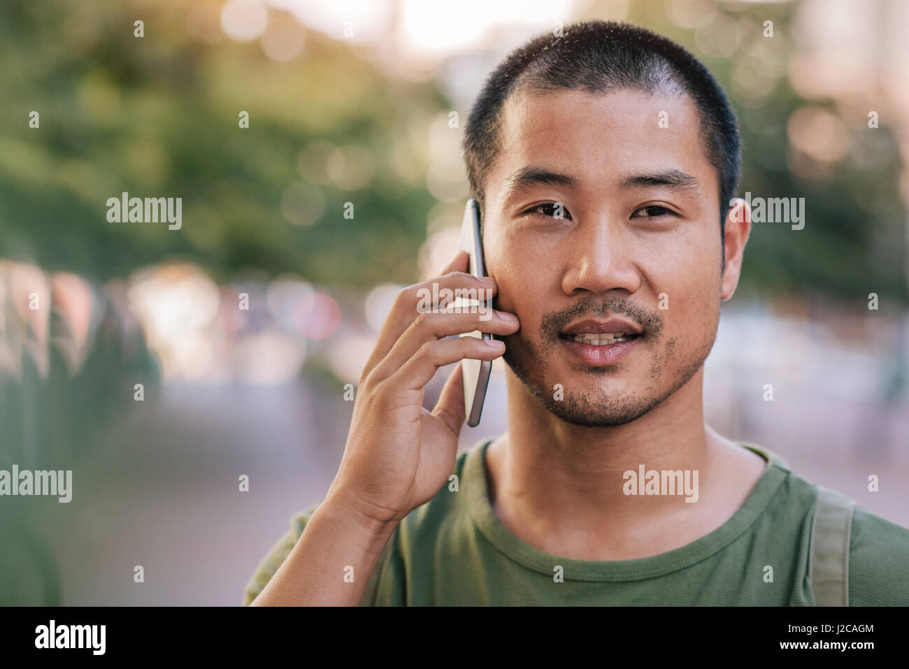Schöner asiatischer Mann auf seinem Handy im freien sprechen Stockfoto