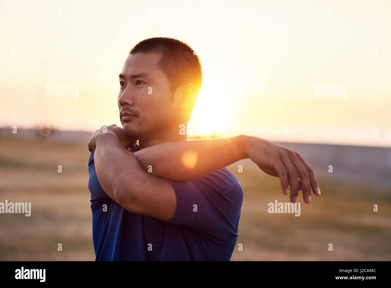 Sportlicher asiatischen Mann dehnen die Schultern vor einem Morgenlauf Stockfoto