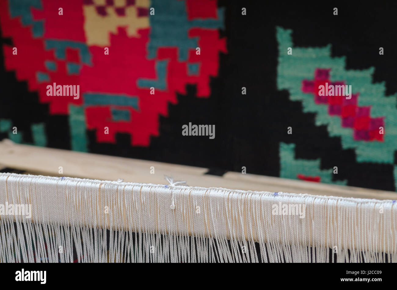 Hintergrund Teil des Teppichs aus Wolle und die Kettfäden auf dem Webstuhl Stockfoto