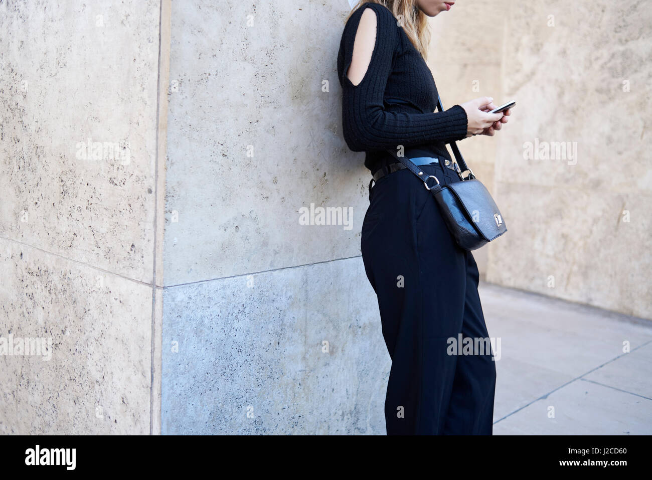 Frau mit schwarzen Overall mit Smartphone in der Straße Stockfoto