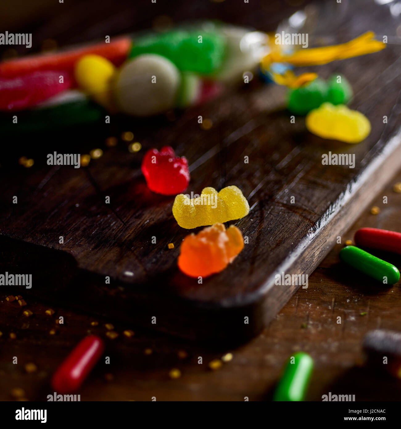 Nahaufnahme von einige Süßigkeiten mit verschiedenen Geschmacksrichtungen und Farben auf eine rustikale Schneidbrett aus Holz, auf einem Tisch Stockfoto